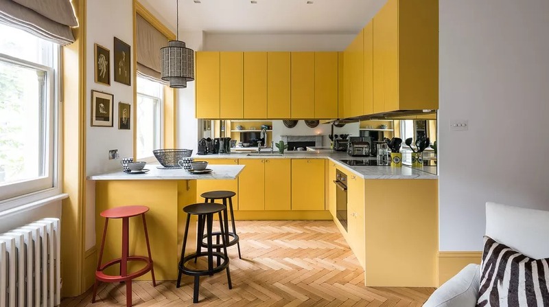 Không gian nhà bếp màu vàng tươi tắn với mặt bàn bếp và bàn ăn được ốp đá sang trọng và sạch sẽ, rất phù hợp với chủ nhà mệnh Thổ