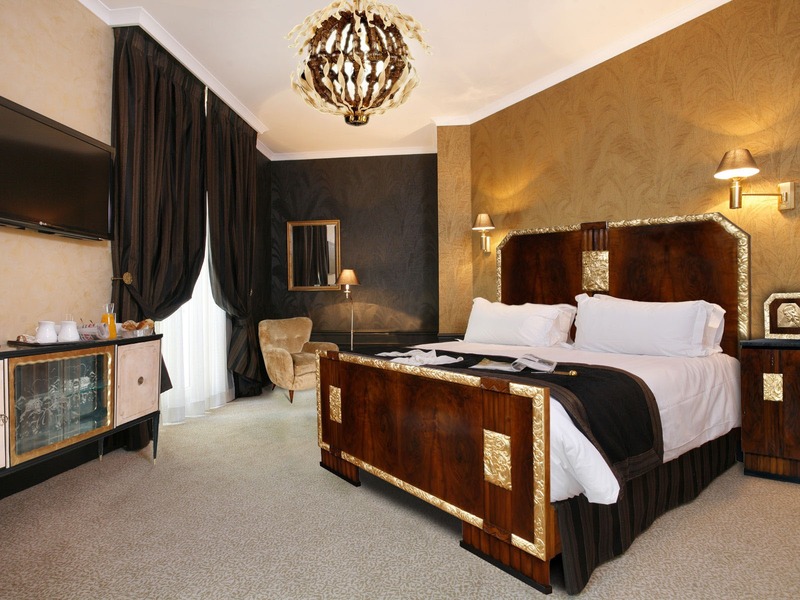 Phòng ngủ sử dụng nội thất gỗ chủ đạo, kết hợp với các chi tiết vàng kim và đèn ngủ màu vàng cam gợi lên bầu không khí ấm áp