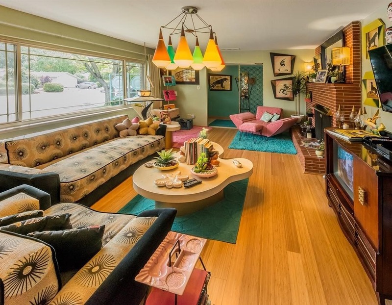 Không gian nội thất phòng khách mang phong cách Retro sử dụng bộ ghế sofa với hoạ tiết ấn tượng, chiếc đèn chùm màu sắc hài hoà với màu sàn gỗ